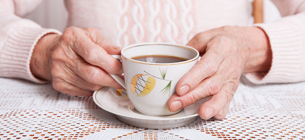 Une femme âgée tient une tasse de café